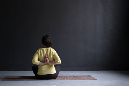 back view of mature woman in sweater sitting in yoga poseの写真素材