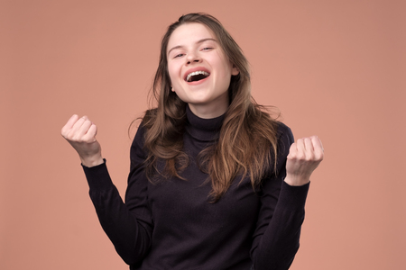 Happy young woman gesturing and keeping fists up.の写真素材