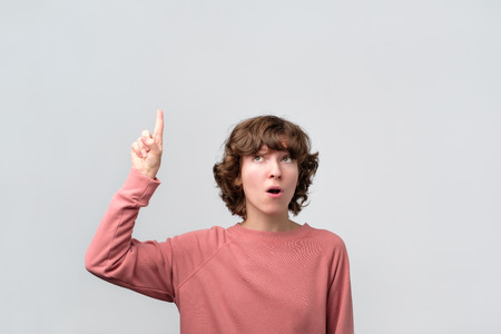 Attractive young curly woman pointing up. Studio shoot.の写真素材