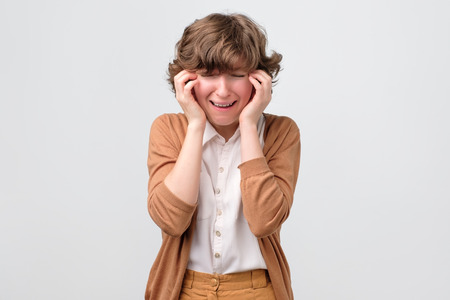 Displeased crying young woman putting hand on headの写真素材