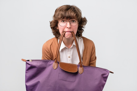 Funny woman in glasses holding shopping bags with her teeth.の写真素材