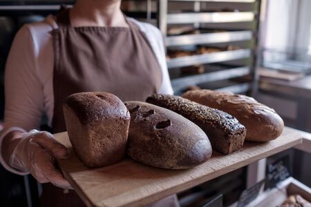 Seller holding a tray with fresh loaf of different bread