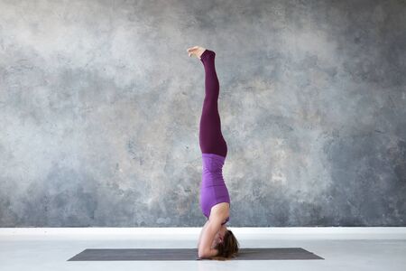 woman practicing yoga, standing in salamba sirsasana exercise, headstand pose