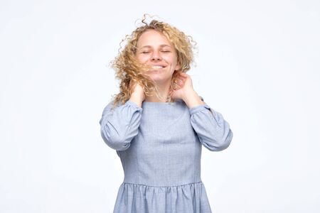 Curly haired woman in dress with perfect skin and smile.