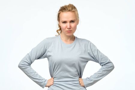 Displeased angry teenager holding hands on hips, frowning, looking with contemptの写真素材