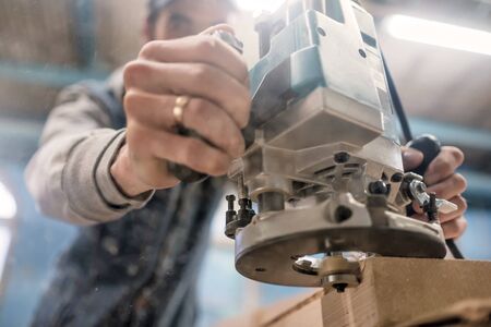 Carpenter using electric woodworking routing a wooden plankの写真素材