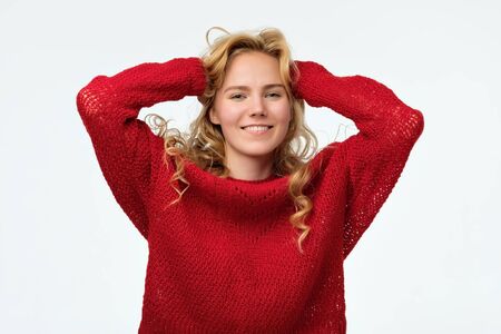 Beautiful blond teenage girl smiling broadly in red sweater.の写真素材