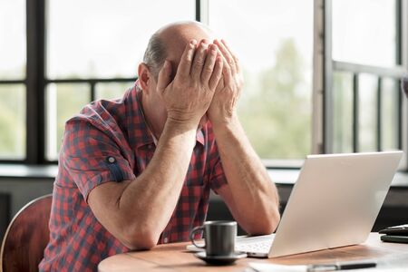 Man rubbing his tired eyes. He is tired to look on laptop screen