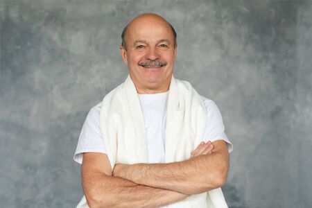 Senior hisanic man after shaving standing with white towel and smiling.の写真素材