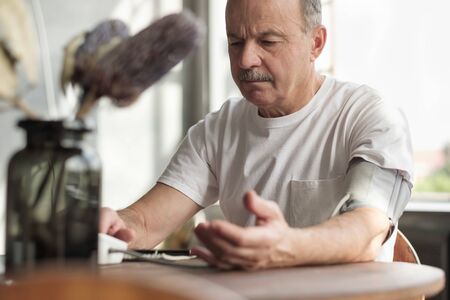 Man using home blood pressure machine to check his vital statistics.の写真素材