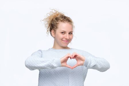 Smiling cheerful happy young woman making heart sign with hands