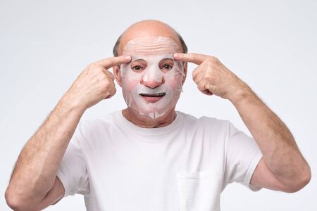 Hispanic mature man in a cosmetic mask skin care. Studio shot. take care about health at old age.の写真素材