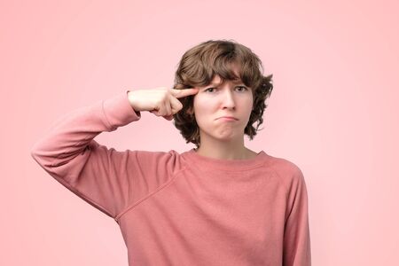 Funny mature female generates new idea in mind, looks thoughtfully at camera isolated over pink...