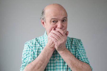 Mature senior hispanic men covering his mouth by hand