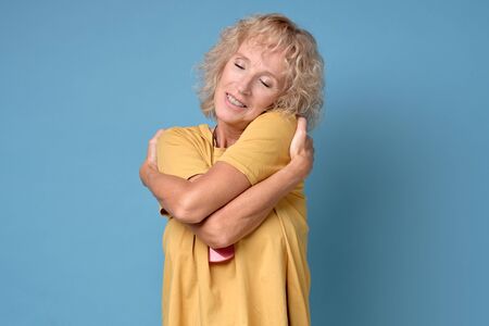 Mature blonde beautiful woman wearing yellow t-shirtの写真素材