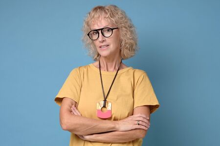 Woman is looking at camera and smiling with folded hands.の写真素材