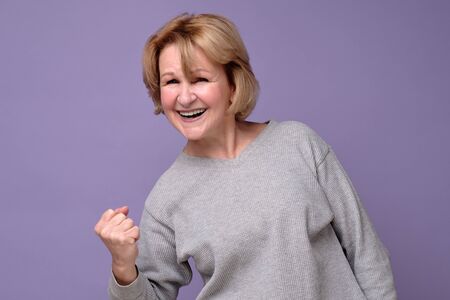 Senio female winner raising arm, clenching fist, exclaiming with joyの写真素材