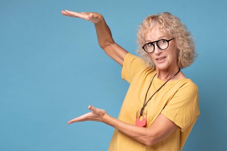 Happy smiling beautiful mature woman making hands the size of big thing.の写真素材