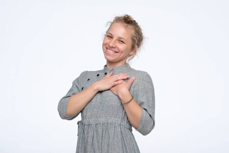 Young woman touching heart looking camera laughing pleasedの写真素材