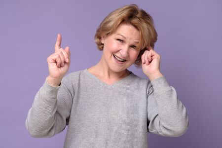 Funny middle age mature woman pointing with finger up giving adviceの写真素材