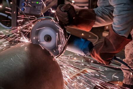 Man in protective gloves cutting metal using angle grinder making sparks