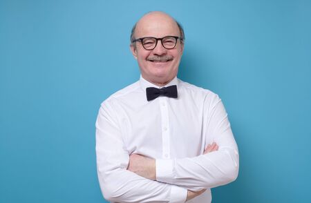 Happy hispanic bald man in glasses smiling at camera standing with folded hands.の写真素材