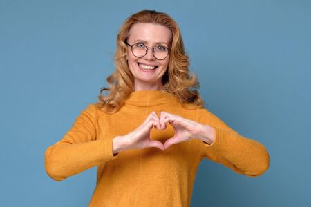 Mature caucasian woman with glasses formed a heart with the hands being in love having healthy...