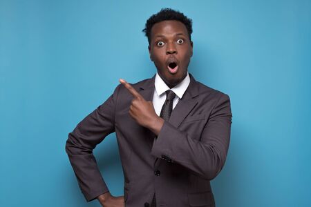 Black african american shocked man point aside and looking at the cameraの写真素材