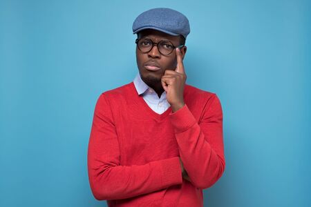 African man touching his chin, looking thoughtful and skeptical about somethingの写真素材