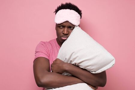 Low energy tired adult african man looiing aside peeping through sleeping mask