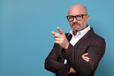 Handsome mature italian businessman in glasses pointing and looking at camera