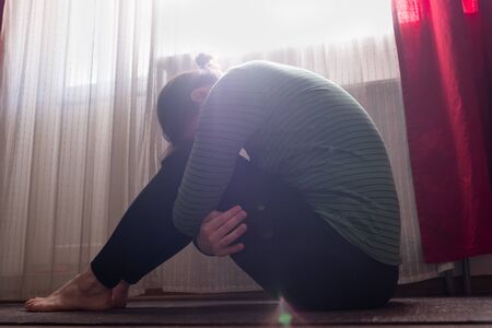Sporty girl sitting at the living room in Balasana, Child Pose variation, yoga for relieving stress,...