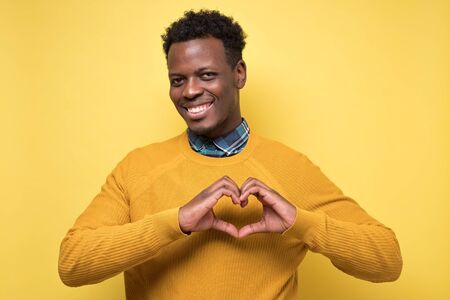 man making a heart with his hands on yellow wallの写真素材