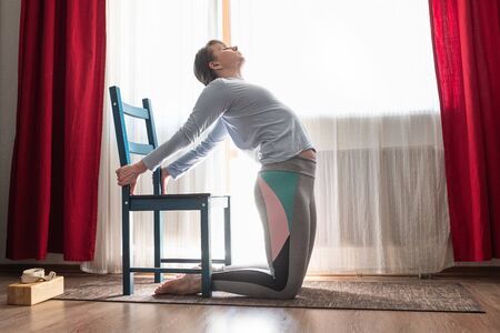attractive woman inbackbend yoga pose, Ushtrasana in therapy variation.の写真素材