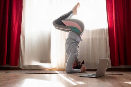 woman doing yoga exercise variation of supported headstand, salamba sirsasana