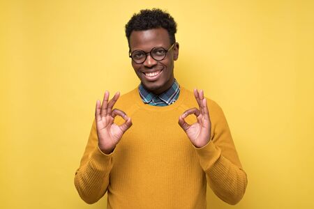 Portrait of happy african american man in glasses showing ok sign and smiling
