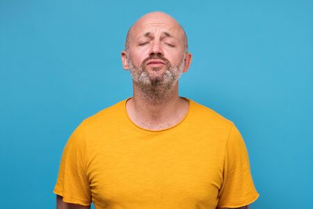 Handsome guy with folded lips waiting for kiss, standing over blue background.の写真素材