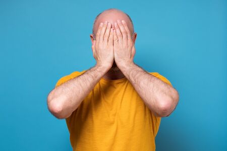Caucasian mature man covered his face with hand feeling stressed and aloneの写真素材