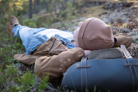 Restful young man laying down on the ground of a forestの写真素材