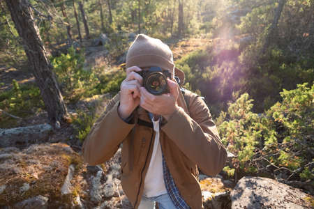 Male tourist using digital camera outdoors in a forest