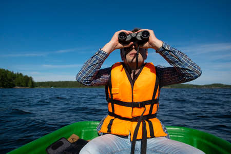 Man in the boat looks in the binoculars