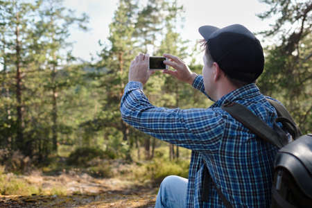 Man makes photos on a smartphone in the forest during hikingの写真素材