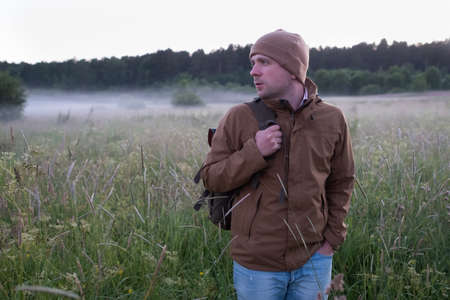 Man walking in a misty meadow hiking in the evening.の写真素材