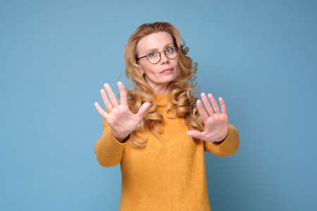 Stressed out angry mature woman keeping hands in stop gestureの写真素材
