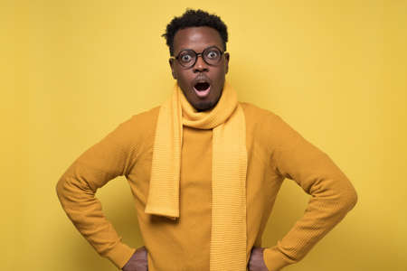 African man in yellow sweater and scarf with shocked emotional facial expressionの写真素材