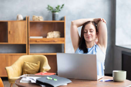 Business woman stretches her body doing yoga exercise at coffee break.