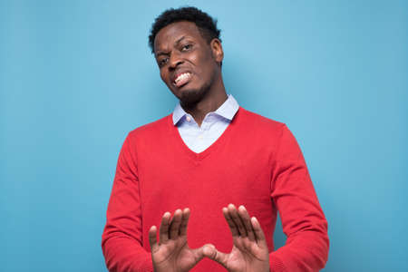 African man making frightened gesture with palms as if trying to defend himself