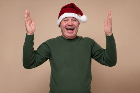 Senior hispanic man with red santa hat smiling.の写真素材