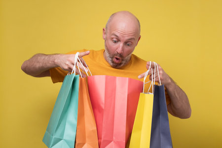 Mature hispanic man with beard holding shopping bags from mall.の写真素材