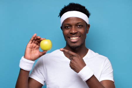 Sportive young african man pointing on an apple.の写真素材